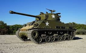 A heavy armored fighting vehicle carrying guns and moving on a continuous articulated metal track.